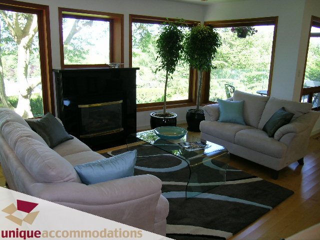 Bright living room with large windows, hardwood floors, and a cozy fireplace. - 3967 West Broadway, Vancouver West Side