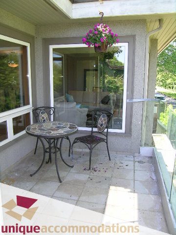 Furnished patio with glass table, chairs, and hanging flower basket. - 3967 West Broadway, Vancouver West Side