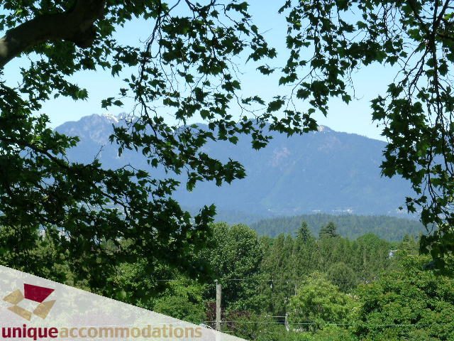 Furnished living room with mountain view and lush greenery. - 3967 West Broadway, Vancouver West Side