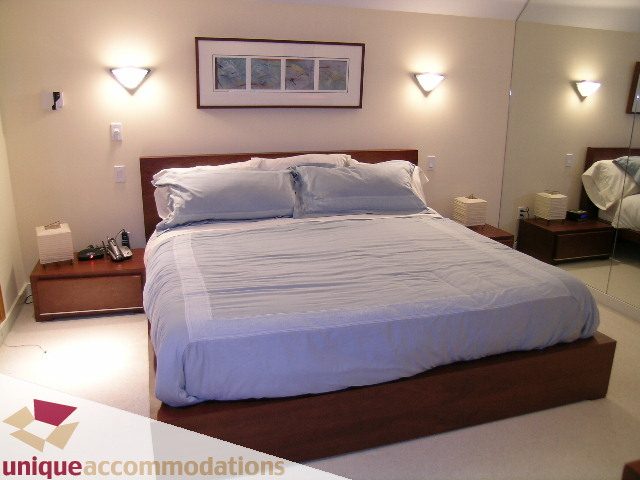 Spacious bedroom with modern furnishings, large bed, and mirrored wall. - 3967 West Broadway, Vancouver West Side