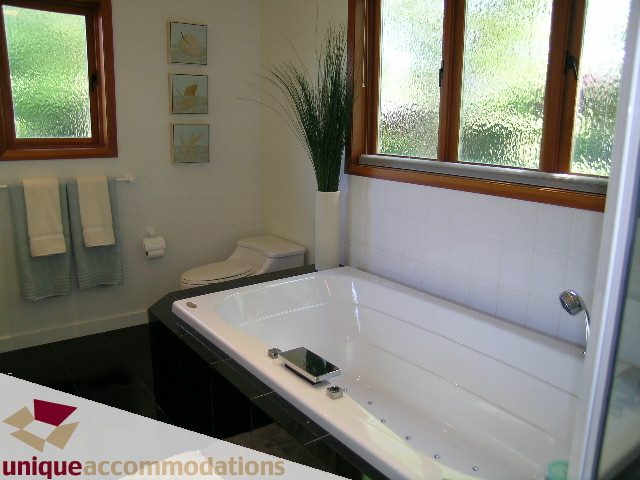 Bright bathroom with a large soaking tub and a view of greenery outside. - 3967 West Broadway, Vancouver West Side
