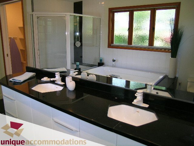 Modern bathroom with black countertops and a large mirror. - 3967 West Broadway, Vancouver West Side