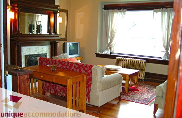 Furnished living room with hardwood floors and a fireplace, featuring a TV and large window. - 1 - 2812 Yukon, Vancouver West Side