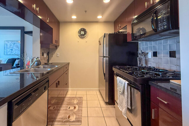 Bright kitchen with black countertops, stainless steel appliances, and a tiled backsplash. - 2602 - 1033 Marinaside Crescent, Vancouver Downtown