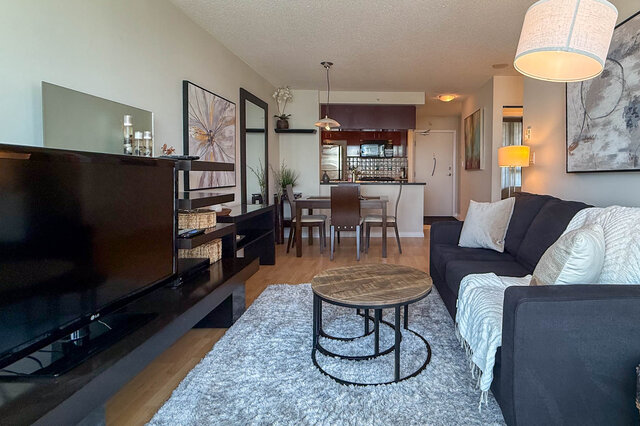Spacious living room with hardwood floors, modern furniture, and a large flat-screen TV. - 2602 - 1033 Marinaside Crescent, Vancouver Downtown