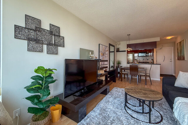 Spacious living room with hardwood floors, modern decor, and a large flat-screen TV. - 2602 - 1033 Marinaside Crescent, Vancouver Downtown