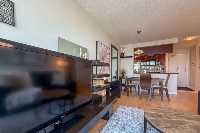 Open-concept living room with hardwood floors, modern furniture, and a view of the kitchen. - 2602 - 1033 Marinaside Crescent, Vancouver Downtown