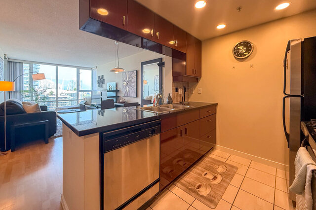 Bright kitchen with modern black countertops, hardwood floors, and a city view. - 2602 - 1033 Marinaside Crescent, Vancouver Downtown