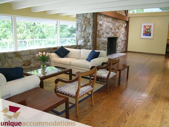 Spacious living room with stone fireplace, hardwood floors, and large windows. - 6189 Nelson Avenue, West Vancouver