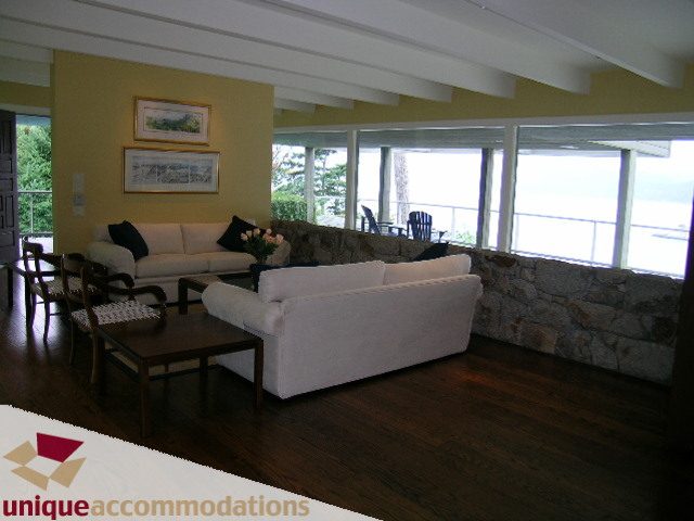 Spacious living room with large windows, hardwood floors, and a stone fireplace. - 6189 Nelson Avenue, West Vancouver