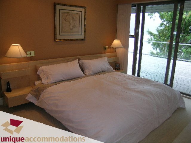 Spacious bedroom with large bed, white linens, and sliding glass door to balcony. - 6189 Nelson Avenue, West Vancouver