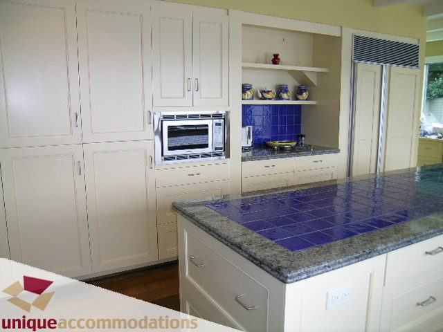 Bright kitchen with white cabinets, blue tiled backsplash, and granite countertops. - 6189 Nelson Avenue, West Vancouver