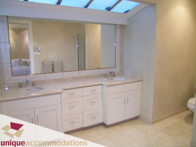 Bright bathroom with dual vanity and large mirrors, featuring a skylight above. - 6189 Nelson Avenue, West Vancouver