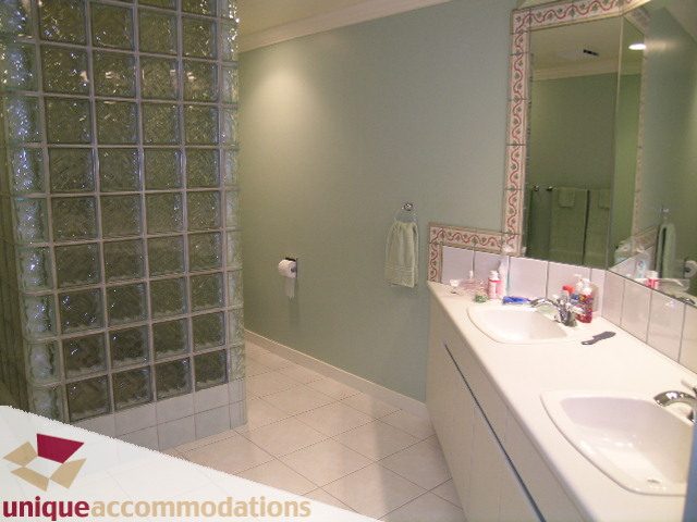 Furnished bathroom with glass block wall, white countertop, and mirror. - 6189 Nelson Avenue, West Vancouver