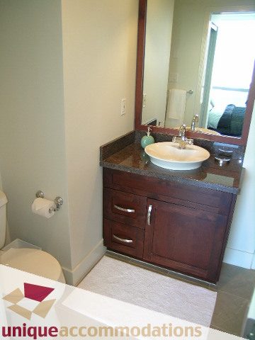 Bathroom with dual sinks, dark wood vanity, and city view mirror. - 302 - 1228 West Hastings Street, Vancouver Downtown