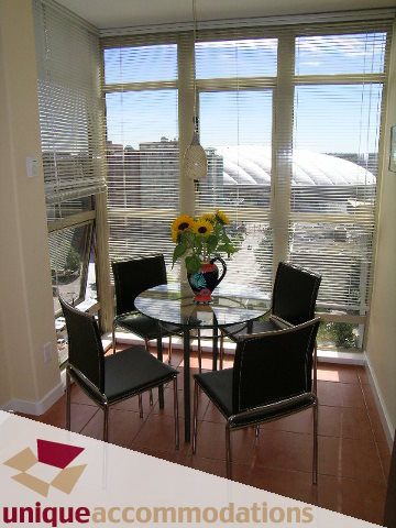 Spacious dining area with city view, sunflowers, and modern furniture. - 1302 - 819 Hamilton Street, Vancouver Downtown