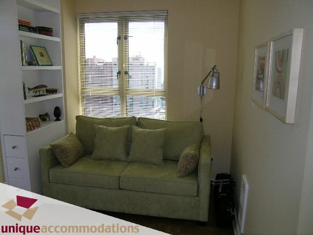 Spacious living room with a cozy green sofa, city view, and modern decor. - 1302 - 819 Hamilton Street, Vancouver Downtown