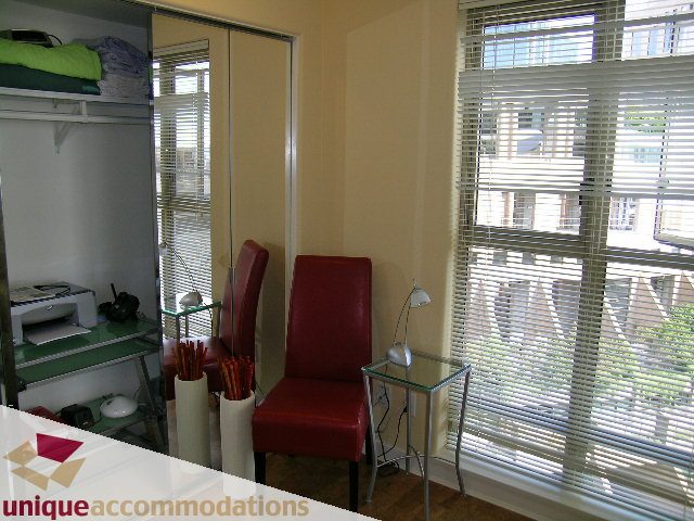 Bright living room with red chairs, glass table, and city view through blinds. - 1302 - 819 Hamilton Street, Vancouver Downtown