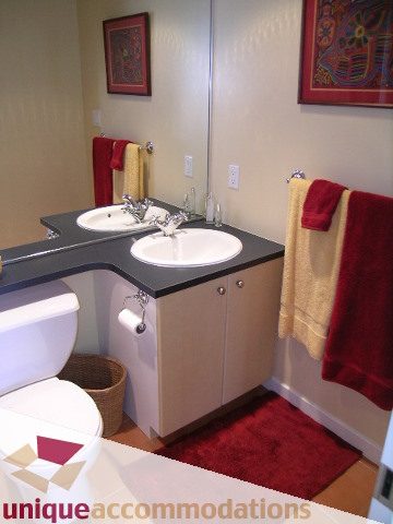 Furnished bathroom with modern sink, red towels, and vibrant artwork. - 1302 - 819 Hamilton Street, Vancouver Downtown