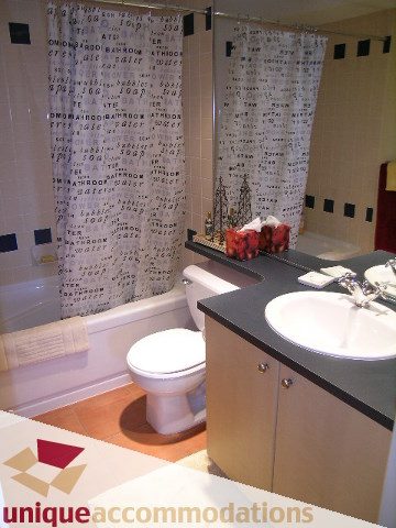 Bathroom with modern decor, white countertop, and patterned shower curtain. - 1302 - 819 Hamilton Street, Vancouver Downtown