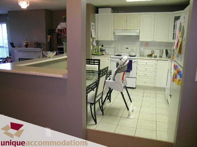 Bright kitchen with white cabinets, tiled floors, and a breakfast bar. - 314 - 855 W. 16th Street, North Vancouver
