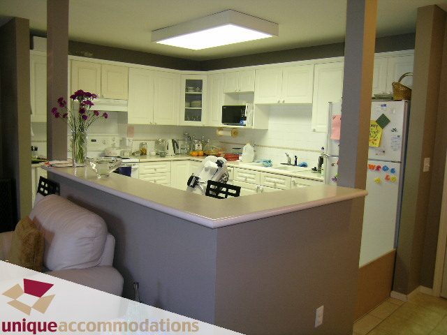 Furnished kitchen with white cabinets and a breakfast bar. - 314 - 855 W. 16th Street, North Vancouver