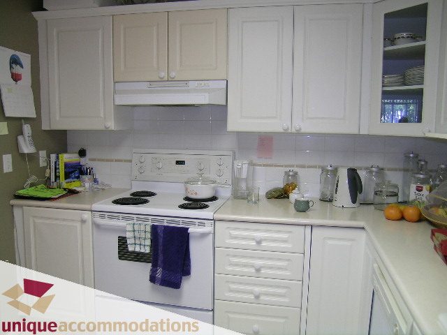 Bright kitchen with white cabinets, countertop, and stove, clean and organized. - 314 - 855 W. 16th Street, North Vancouver