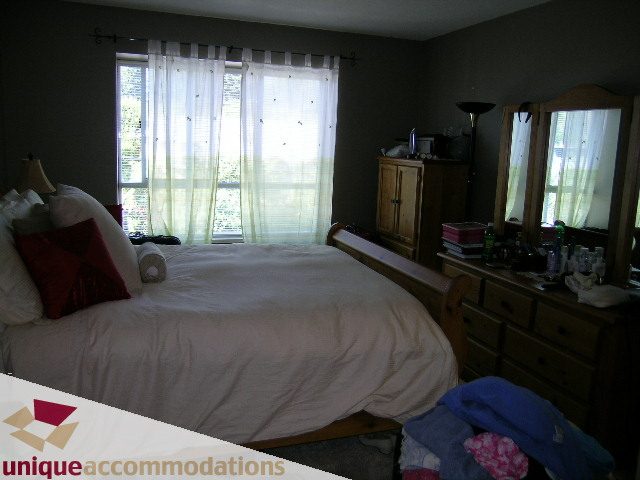 Spacious bedroom with large windows, sheer curtains, and a neatly made bed. - 314 - 855 W. 16th Street, North Vancouver
