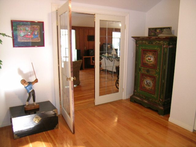Bright living room with hardwood floors, a colorful cabinet, and a glass door leading to another room. - 1250 Seymour Blvd, North Vancouver