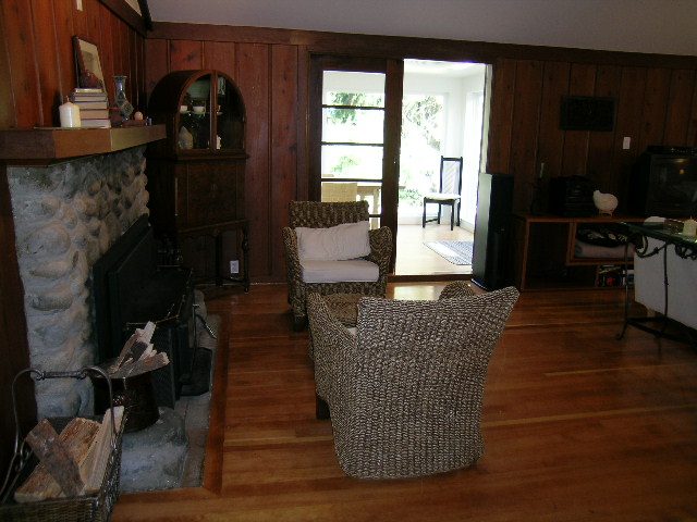 Spacious living room with hardwood floors, stone fireplace, and sliding glass door leading to a patio. - 1250 Seymour Blvd, North Vancouver