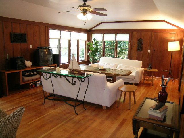 Furnished living room with hardwood floors, white furniture, and a large window. - 1250 Seymour Blvd, North Vancouver