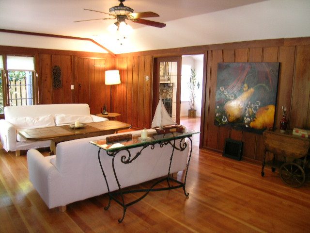 Furnished living room with hardwood floors, white couch, and wooden panel walls. - 1250 Seymour Blvd, North Vancouver