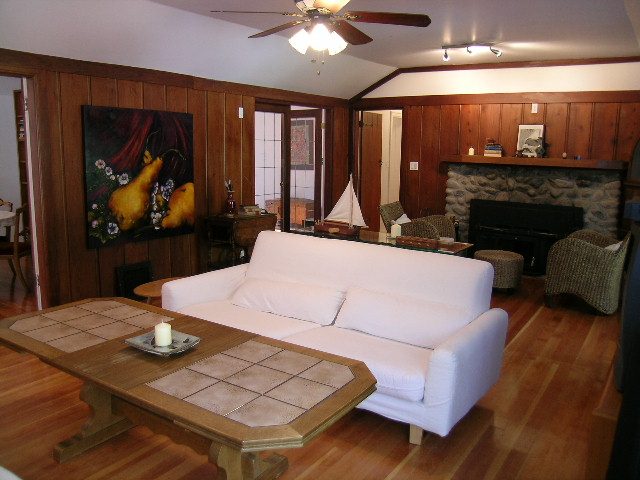 Living room with white furniture, wooden paneling, and a fireplace. - 1250 Seymour Blvd, North Vancouver