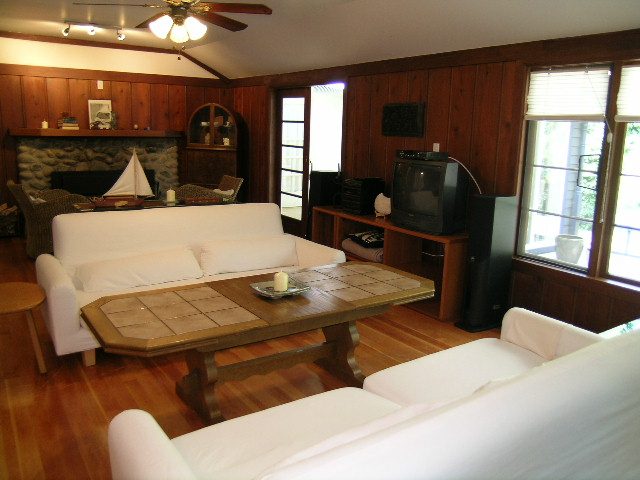 Bright living room with white couch, wooden floors, and a stone fireplace. - 1250 Seymour Blvd, North Vancouver