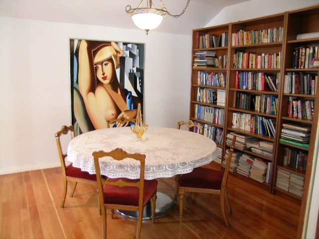 Furnished dining room with wooden floors, bookshelves, and a large abstract painting. - 1250 Seymour Blvd, North Vancouver