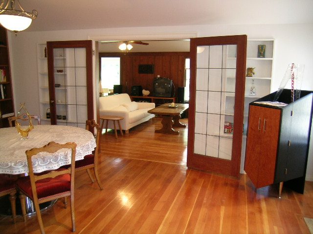Open-concept living and dining area with hardwood floors, a large window, and a cozy sofa. - 1250 Seymour Blvd, North Vancouver