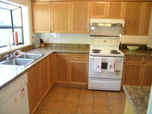 Bright kitchen with wooden cabinets, granite countertops, and a city view. - 1250 Seymour Blvd, North Vancouver