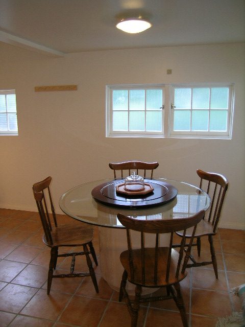 Bright dining area with glass table and wooden chairs, white walls, and large windows. - 1250 Seymour Blvd, North Vancouver