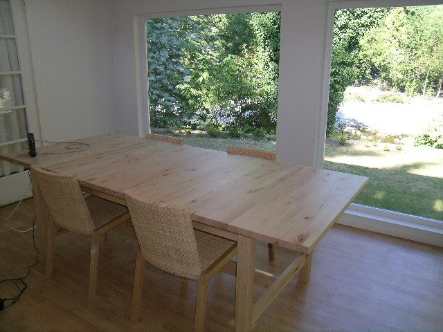 Dining area with wooden table and chairs, hardwood floors, and a view of greenery outside. - 1250 Seymour Blvd, North Vancouver