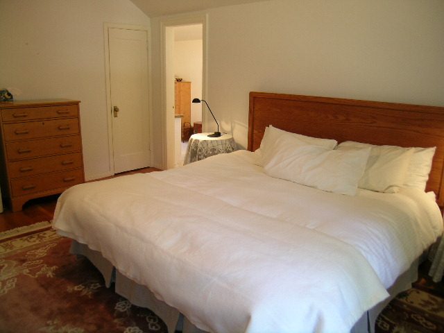 Spacious bedroom with wooden headboard and neatly made beds. - 1250 Seymour Blvd, North Vancouver