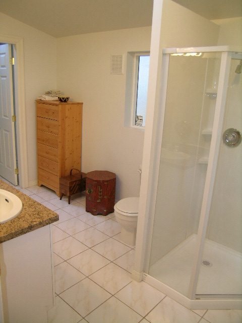 Bathroom with marble countertops and a glass shower enclosure. - 1250 Seymour Blvd, North Vancouver
