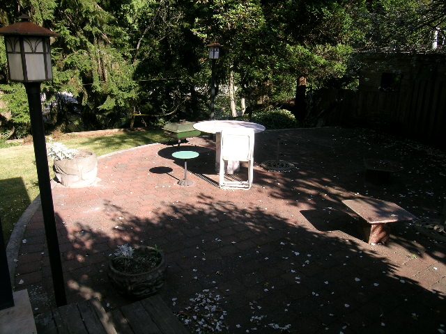 Furnished patio with brick flooring and outdoor seating, surrounded by trees. - 1250 Seymour Blvd, North Vancouver