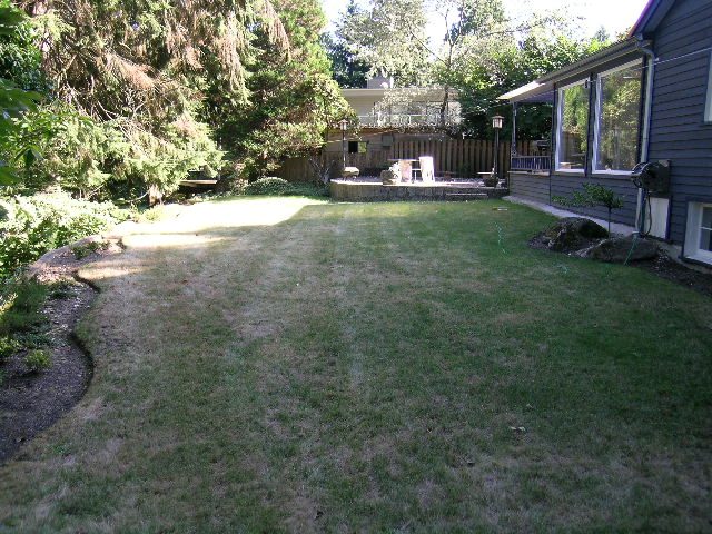 Large, open backyard with grass and a wooden deck. - 1250 Seymour Blvd, North Vancouver