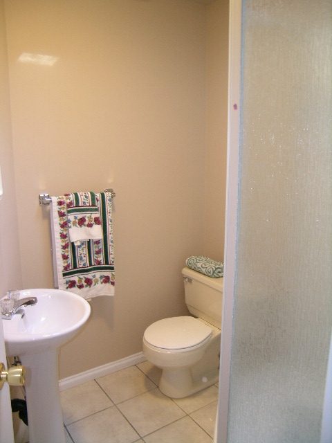 Small bathroom with white sink, toilet, and floral towels. - 1250 Seymour Blvd, North Vancouver
