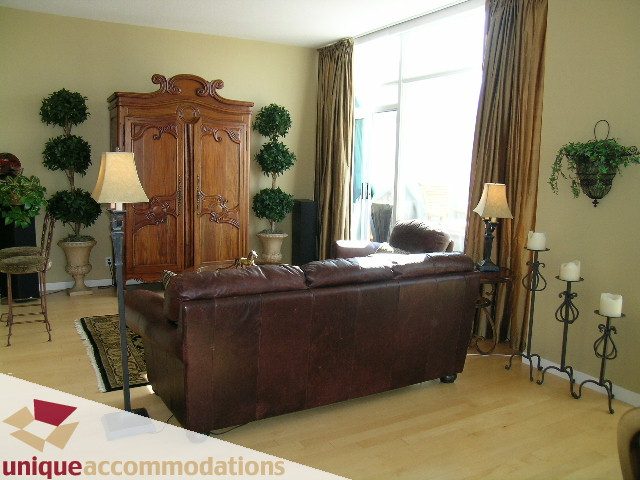 Bright living room with hardwood floors, leather furniture, and large windows. - 3601-193 Aquarius Mews, Vancouver Downtown
