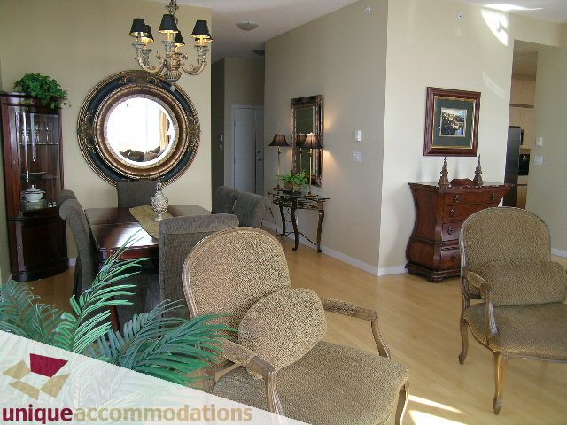 Furnished living room with hardwood floors, wicker furniture, and a large mirror. - 3601-193 Aquarius Mews, Vancouver Downtown