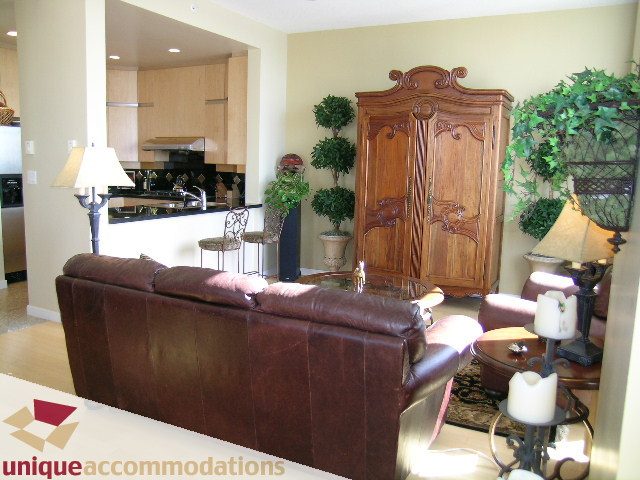 Furnished living room with leather couch, armoire, and kitchen in background. - 3601-193 Aquarius Mews, Vancouver Downtown