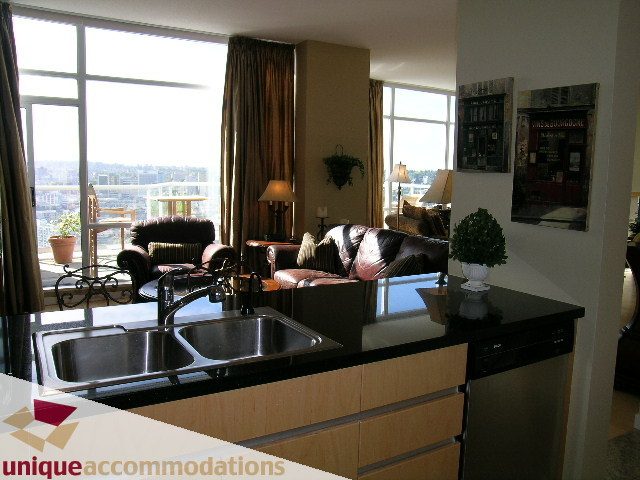 Bright kitchen with modern appliances and city view, featuring wooden cabinets and a large window. - 3601-193 Aquarius Mews, Vancouver Downtown