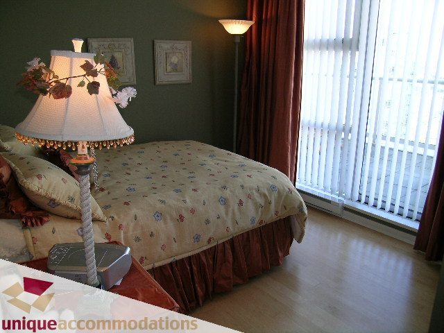 Furnished bedroom with twin beds, hardwood floors, and a city view. - 3601-193 Aquarius Mews, Vancouver Downtown