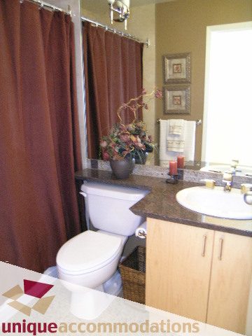 Furnished bathroom with brown curtains, countertop, and wooden cabinets. - 3601-193 Aquarius Mews, Vancouver Downtown